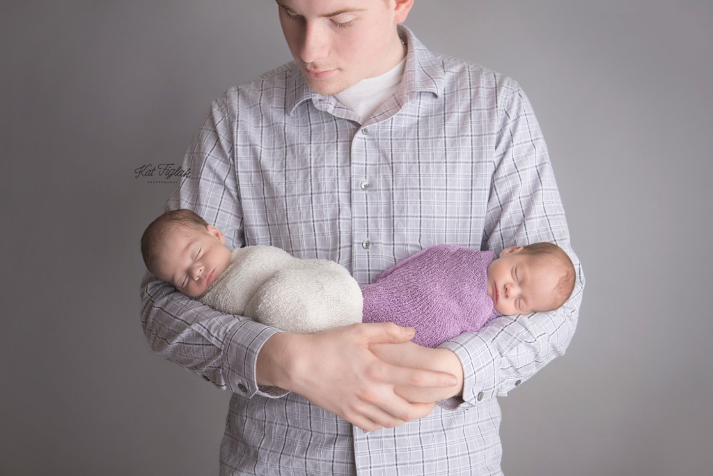 Dad holding newborn twin girls