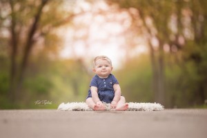 baby girl sitting on trail in navy blue outfit
