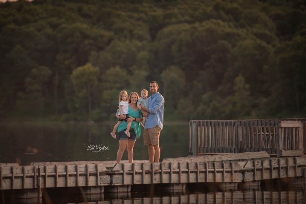 family of four standing on dock during gorgeous summer night