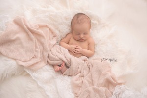baby girl nested in blankets of cream and blush