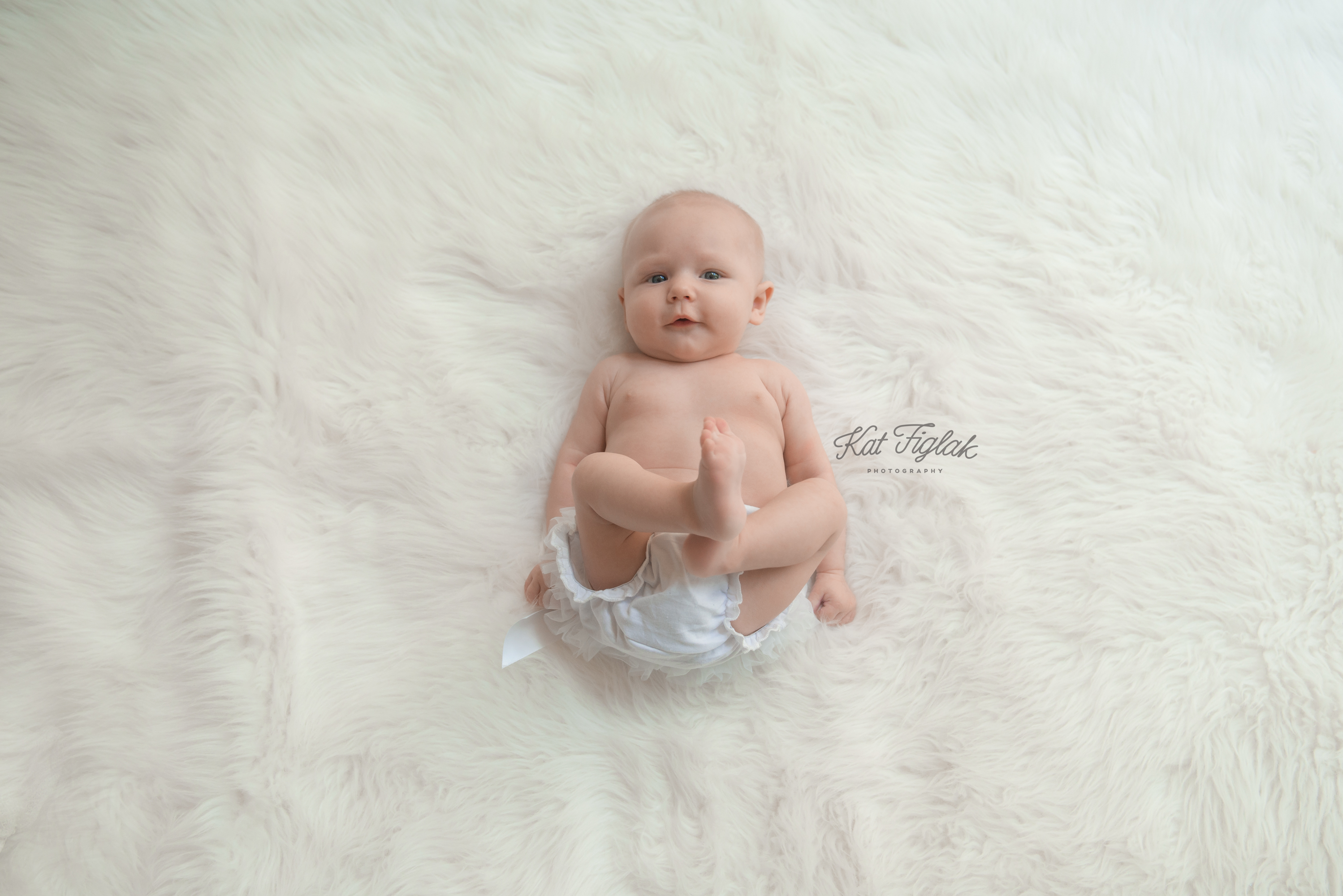 3 month old baby girl laying on white fur rug