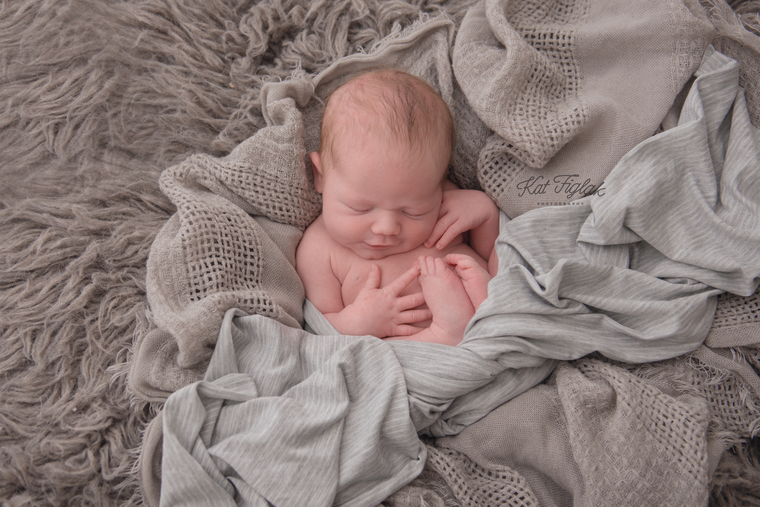newborn baby boy laying in soft gray layers of fabric sleeping