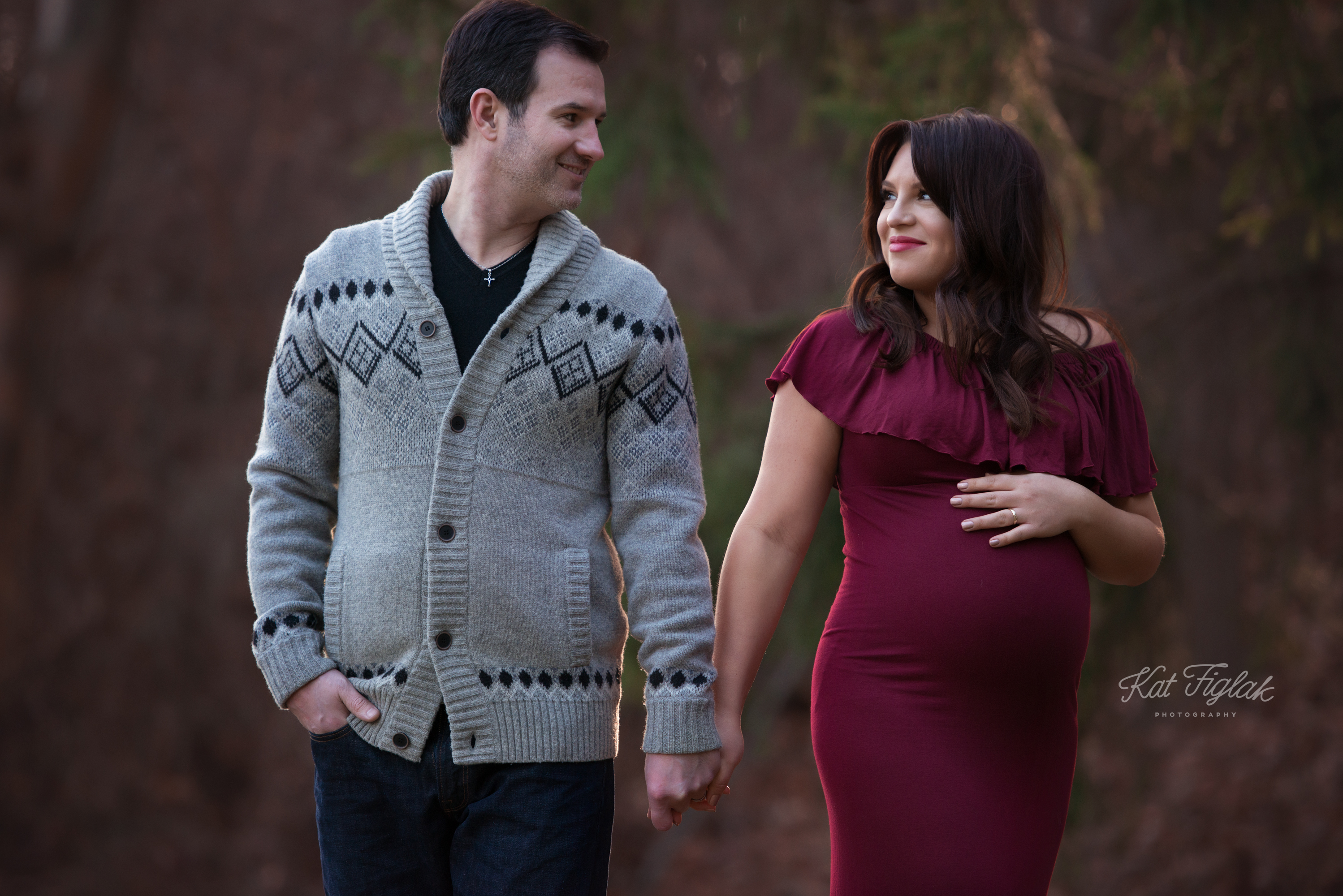 Couple holding hands pregnant mom wearing cranberry off the shoulder dress