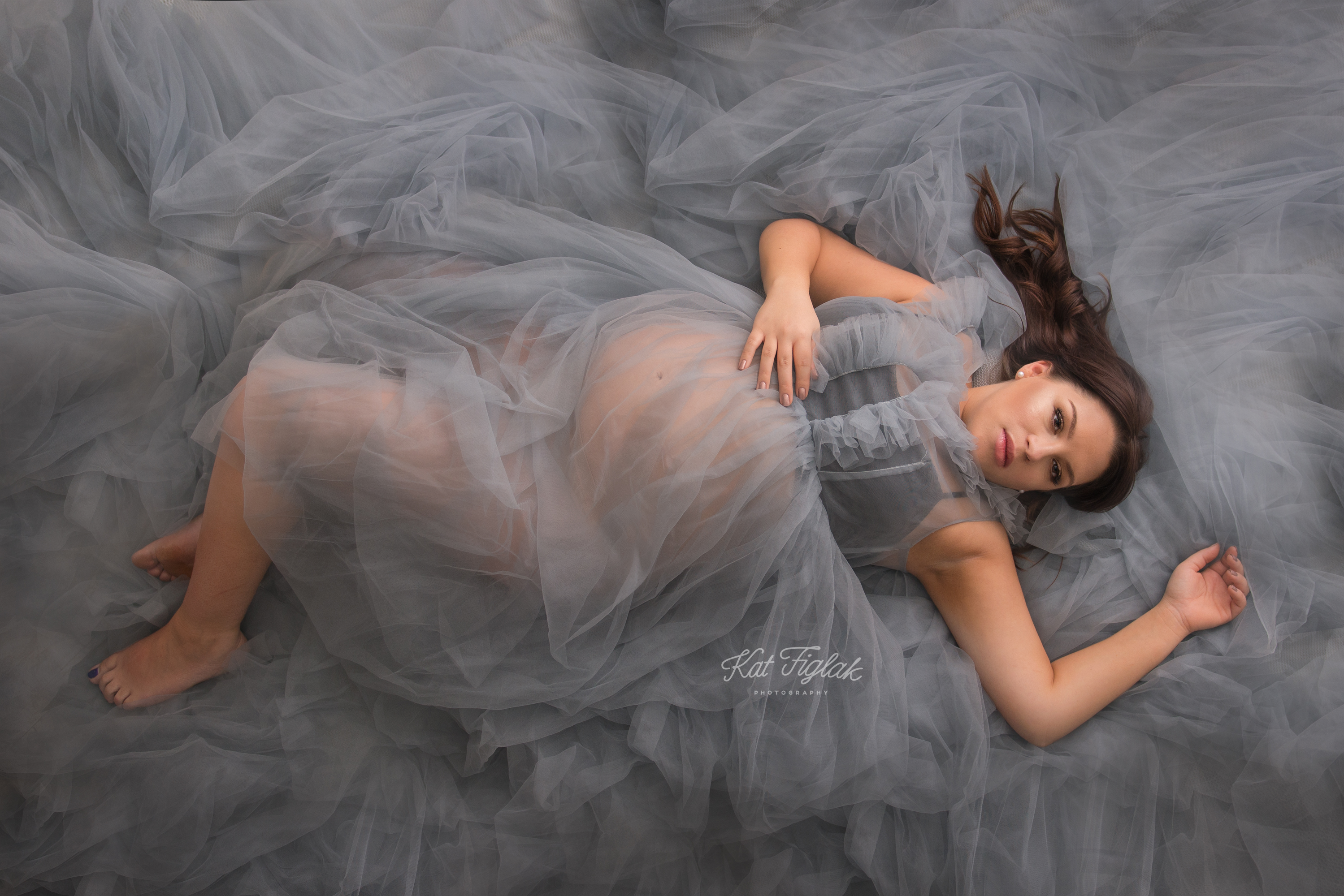 pregnant woman laying down wearing a gray dress