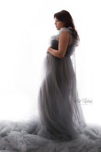 backlit silhouette photo of pregnant woman wearing a shear gray dress