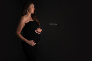 Dark Maternity photo mom to be wearing black dress with black backdrop