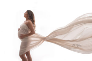 Mom to be draped with sheer cream fabric fanned behind her