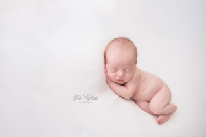 newborn baby boy sleeping posed on a white fabric