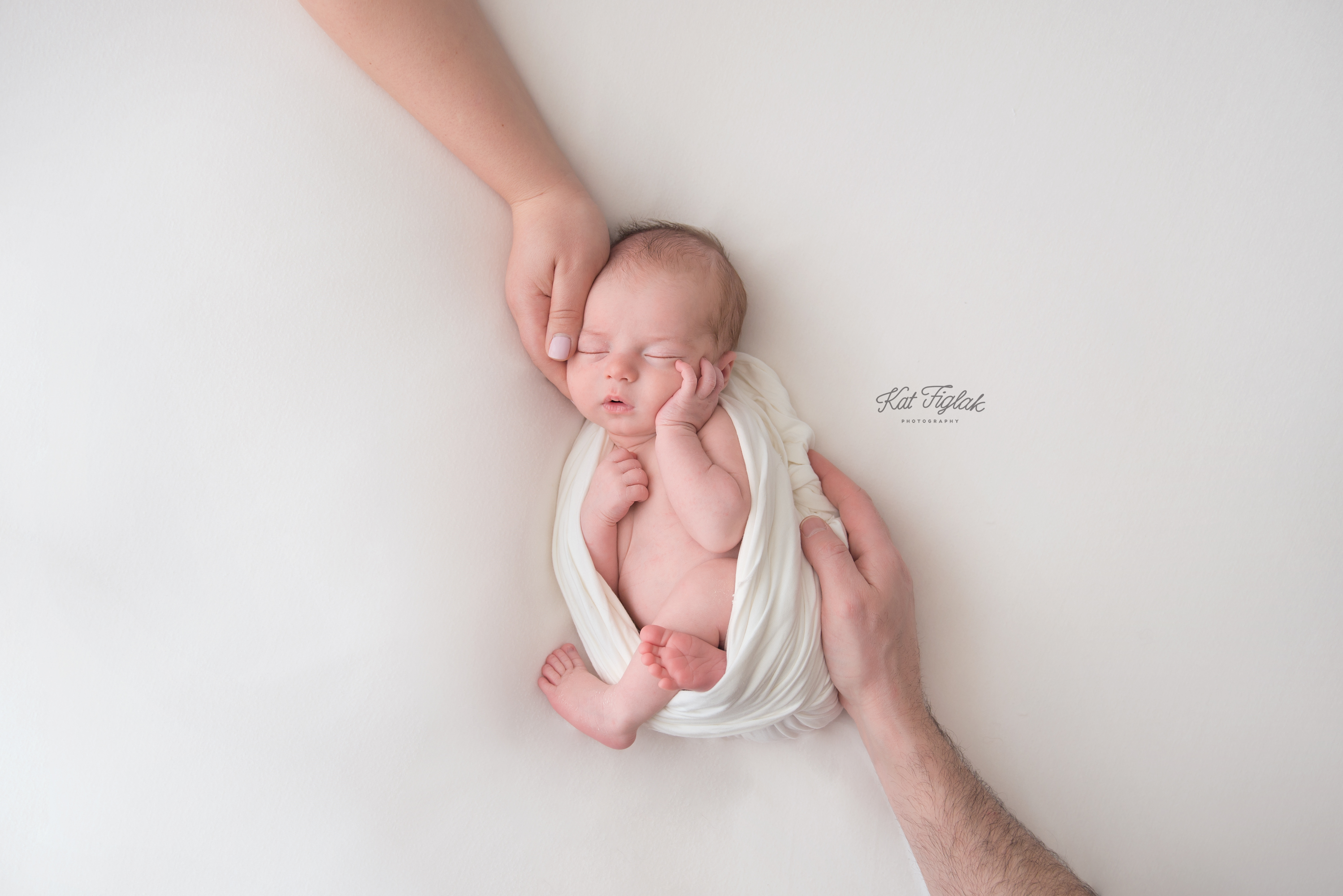 newborn baby boy sleeping on white blanket with both parents hands resting on him