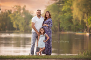 family of 3 standing by a lake waiting for baby boy