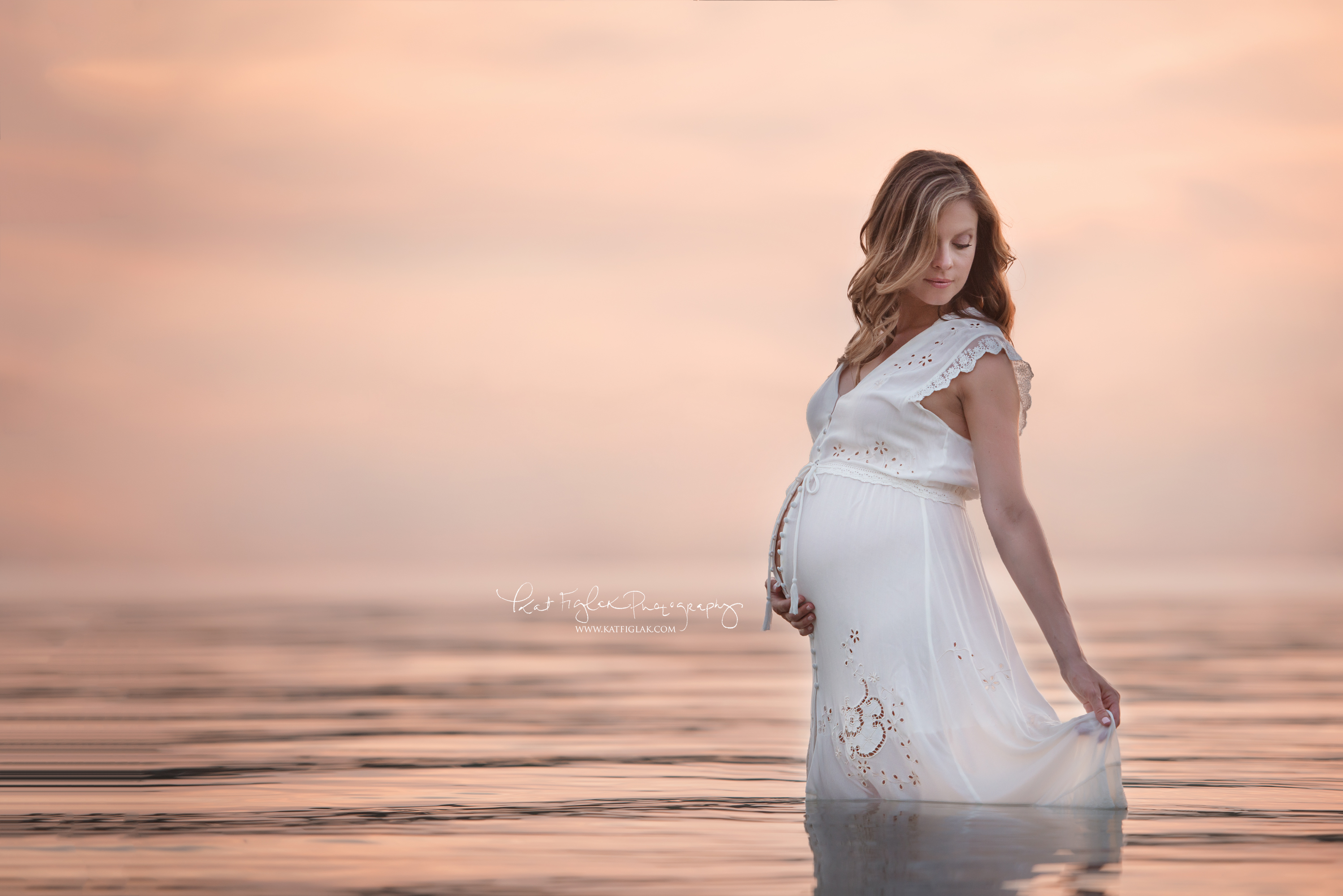 stunning mom standing in lake in a white dress