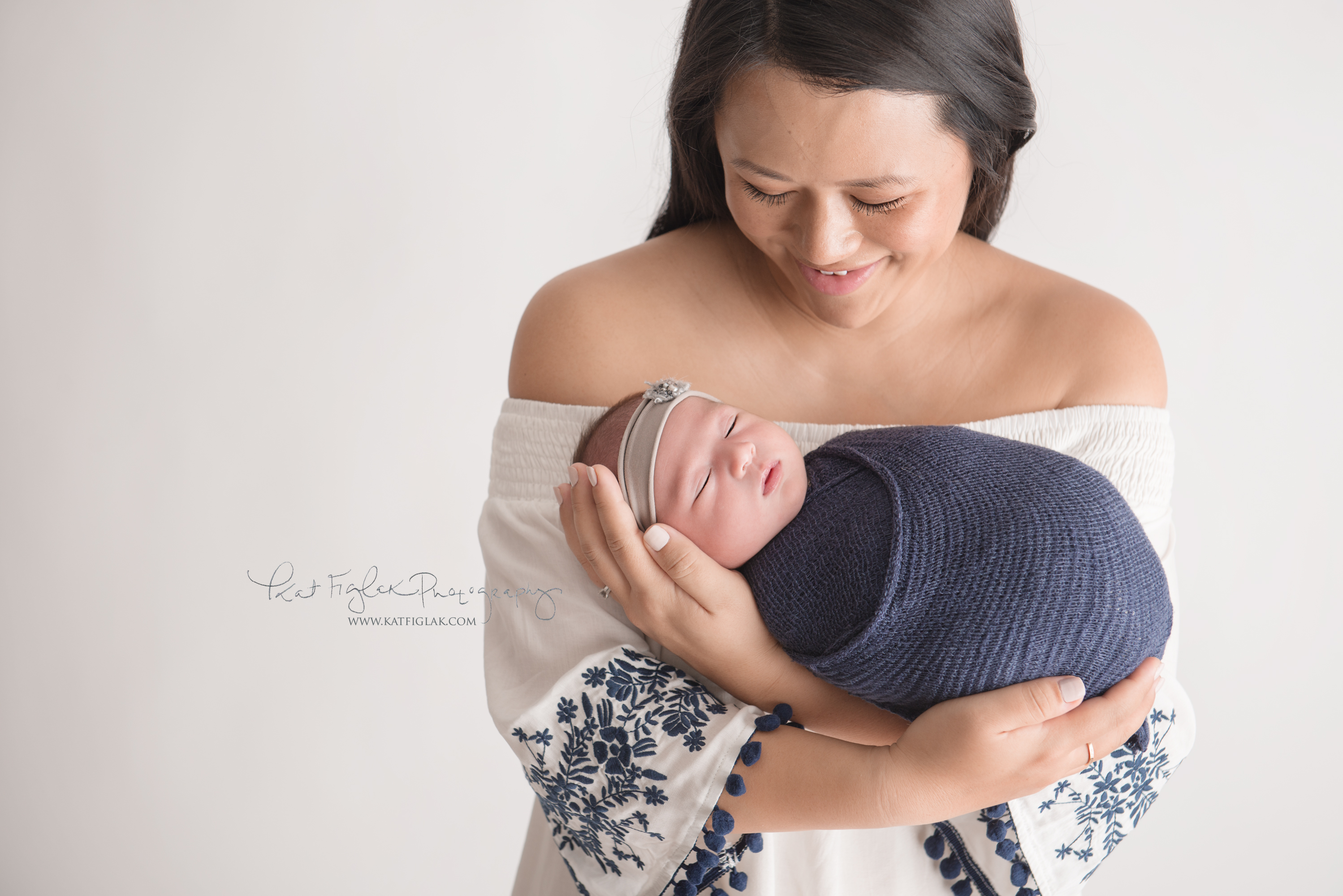 Mom holding her baby girl swaddled in a navy knit wrap