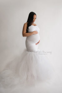 Formal portrait of a pregnant woman wearing a white gown