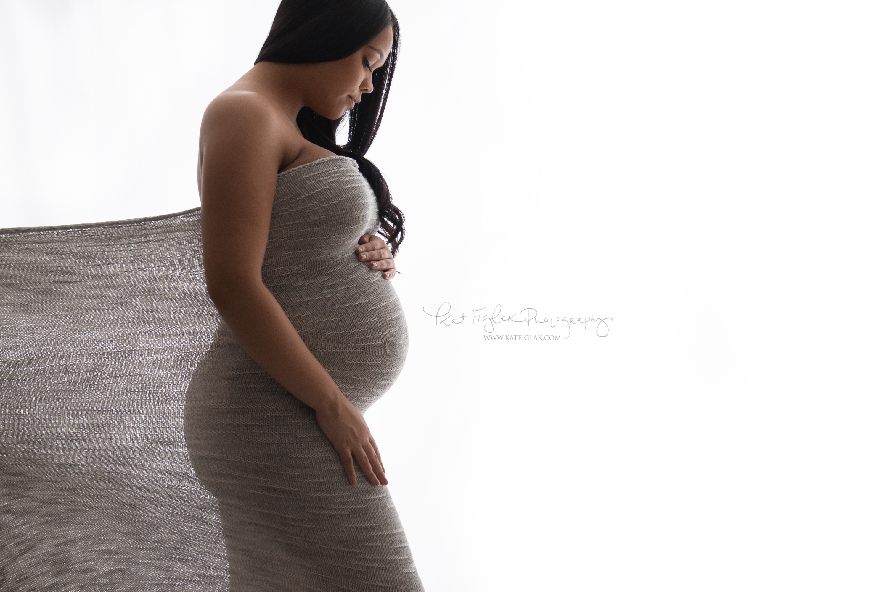 Pregnant mom draped in fabric looking at her belly