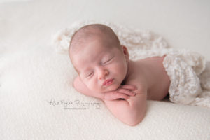 newborn baby girl sleeping with her head on her hands with wrap draped over
