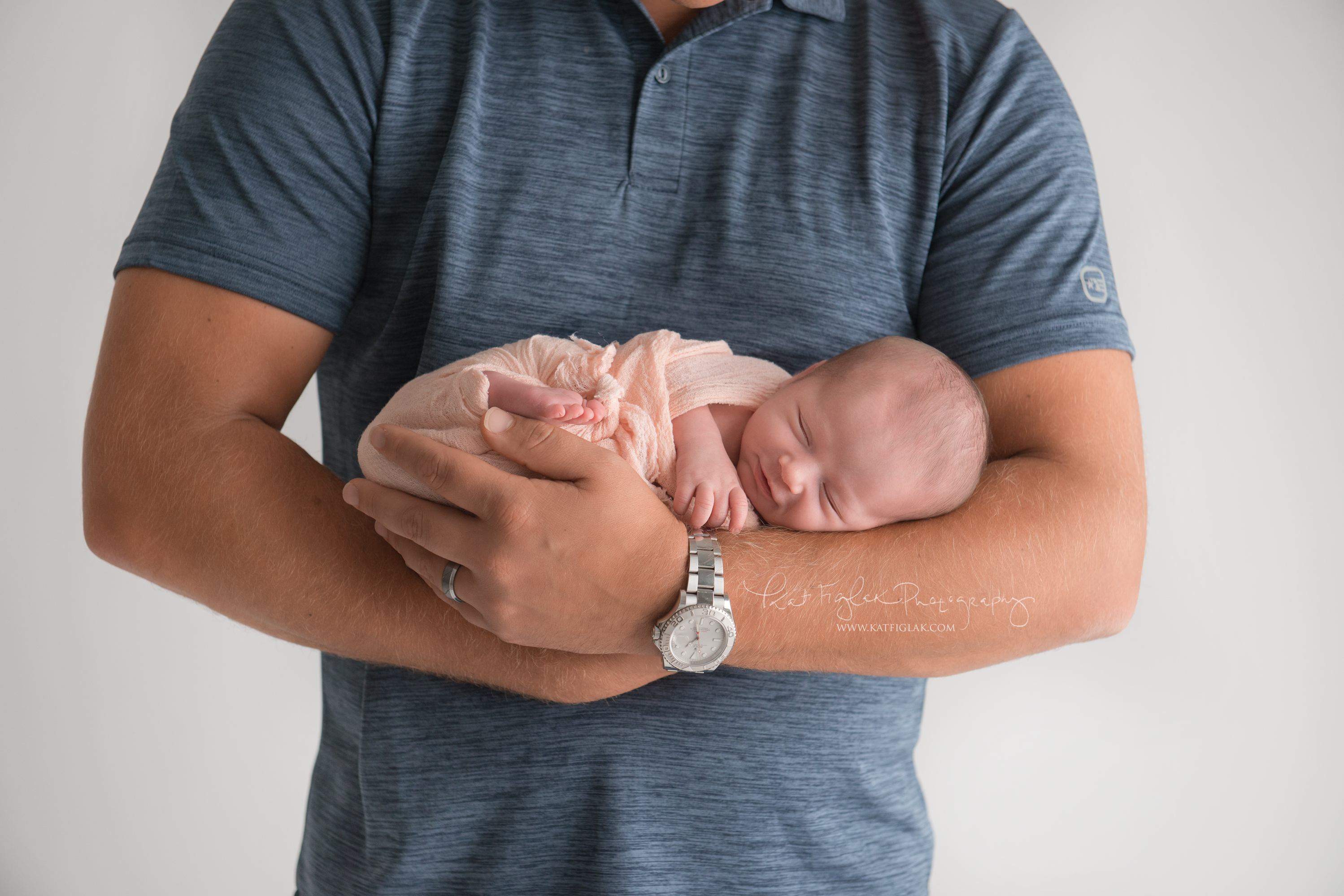 baby girl laying across her dad's arms