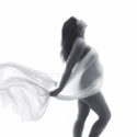 Pregnant mom draped in white silk fabric silhouette shot