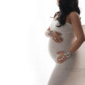Pregnant mom wrapped in white fabric with hand jewelry