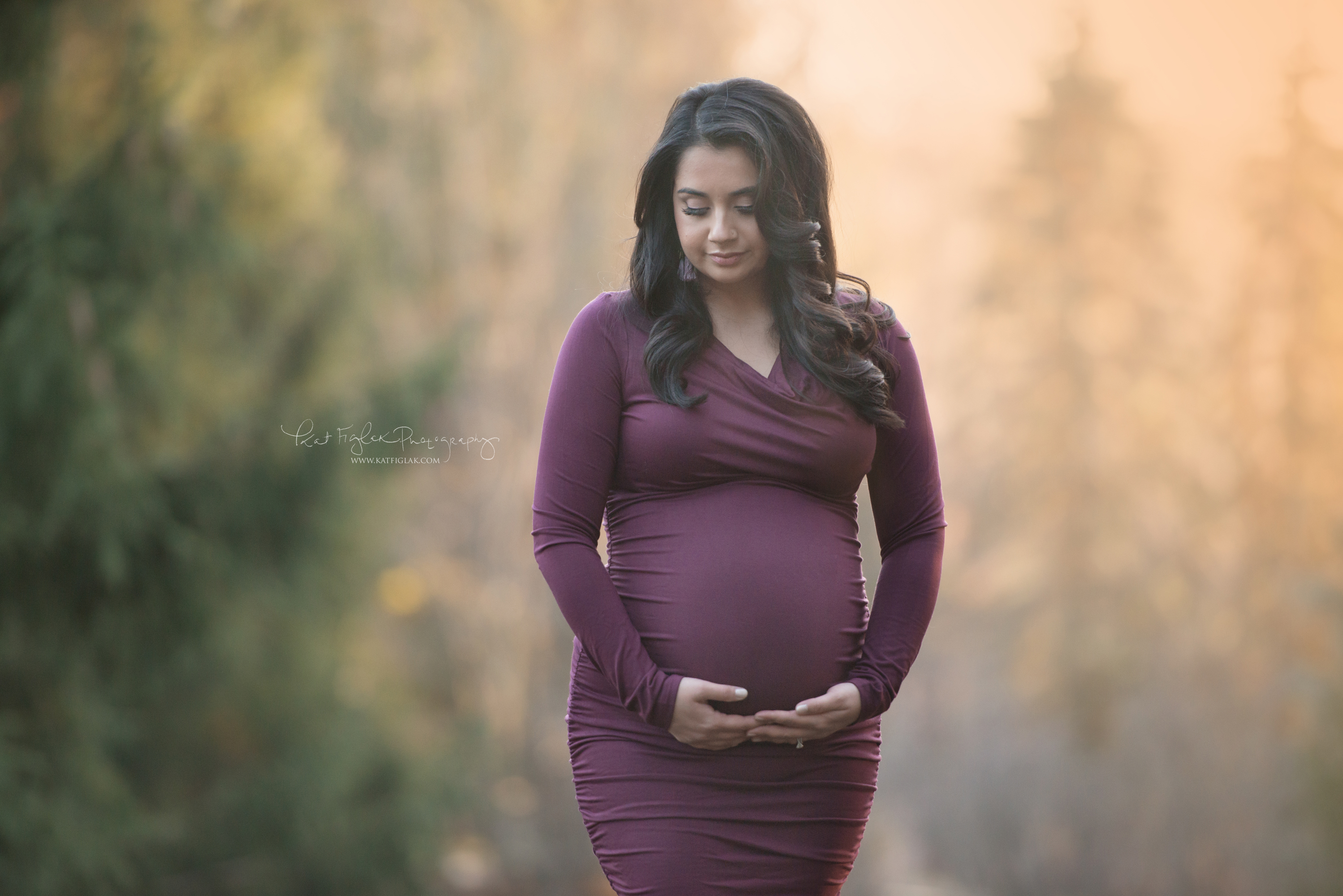 pregnant mom holding her belly wearing a plum dress