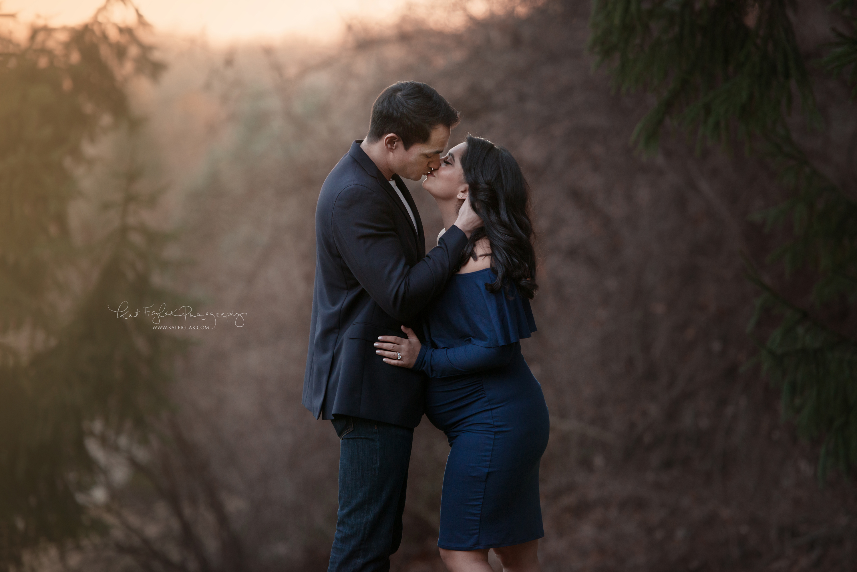 pregnant mom kissing her husband wearing a navy dress