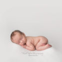 newborn baby boy sleeping on white backdrop