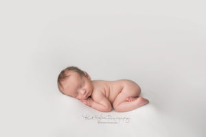 newborn baby boy sleeping on white backdrop