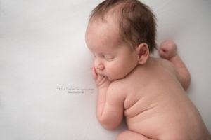 newborn baby boy sleeping on white backdrop close up of his face