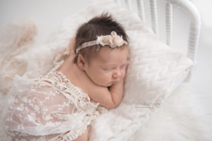 baby girl sleeping on newborn bed draped with lace