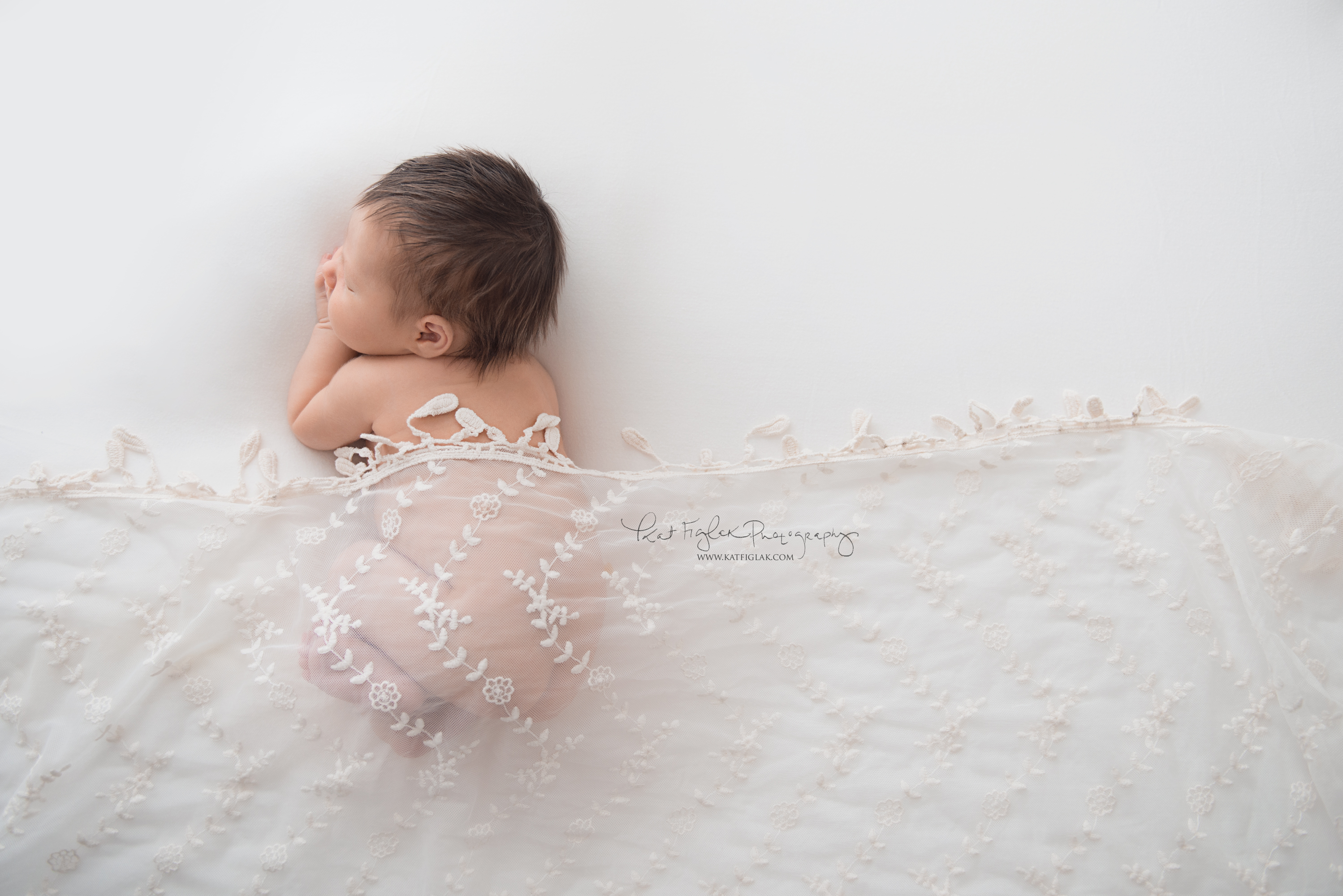 baby girl sleeping on white fabric draped with lace