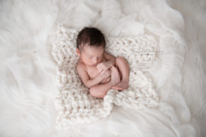 newborn baby boy on rug and soft knits sleeping