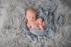 Baby boy wrapped in blue wrap on gray rug