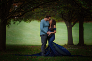 expecting couple kissing wife wearing a navy gown