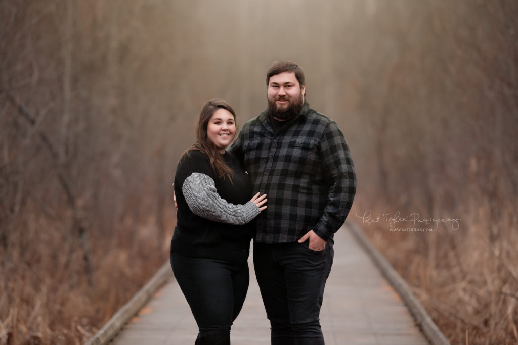 young couple posed on a bridge with fall colors in the background