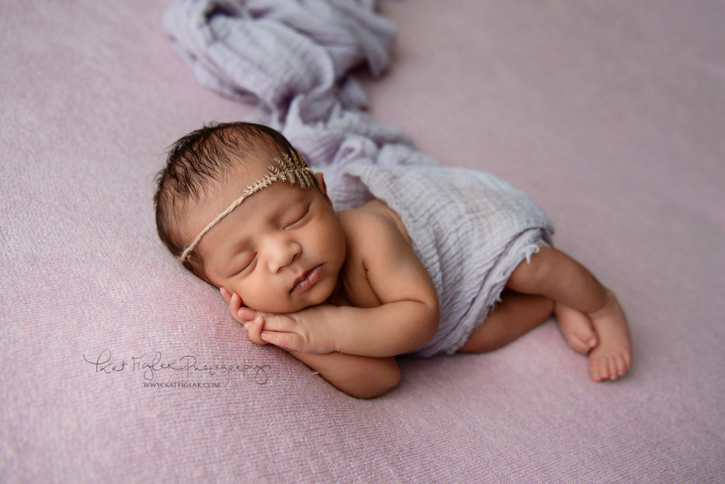 newborn baby girl sleeping wrapped in purple wrap