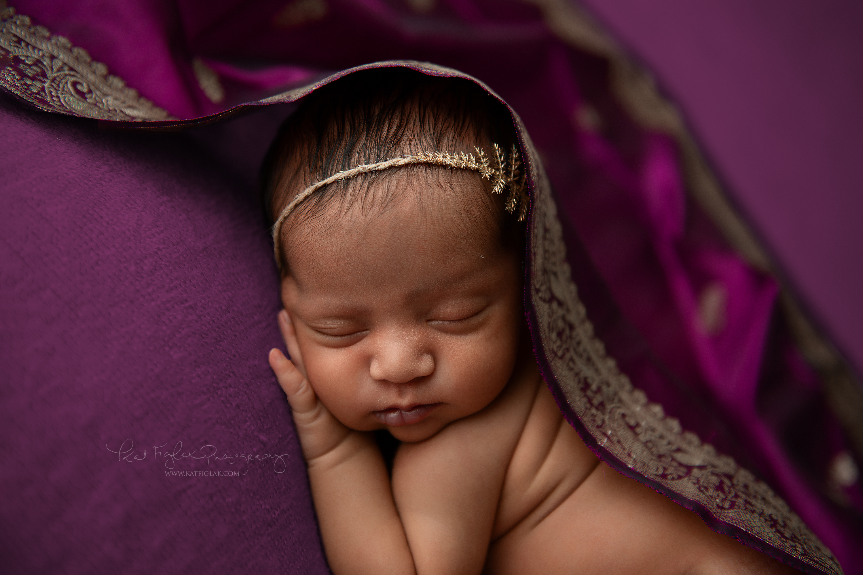 newborn baby girl sleeping on purple blanket covered in silk