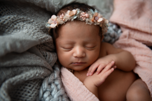 newborn baby girl sleeping wearing a floral pink halo crown