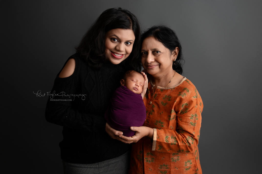 3 generations of women Mom, grandma and baby girl posed together looking at the camera