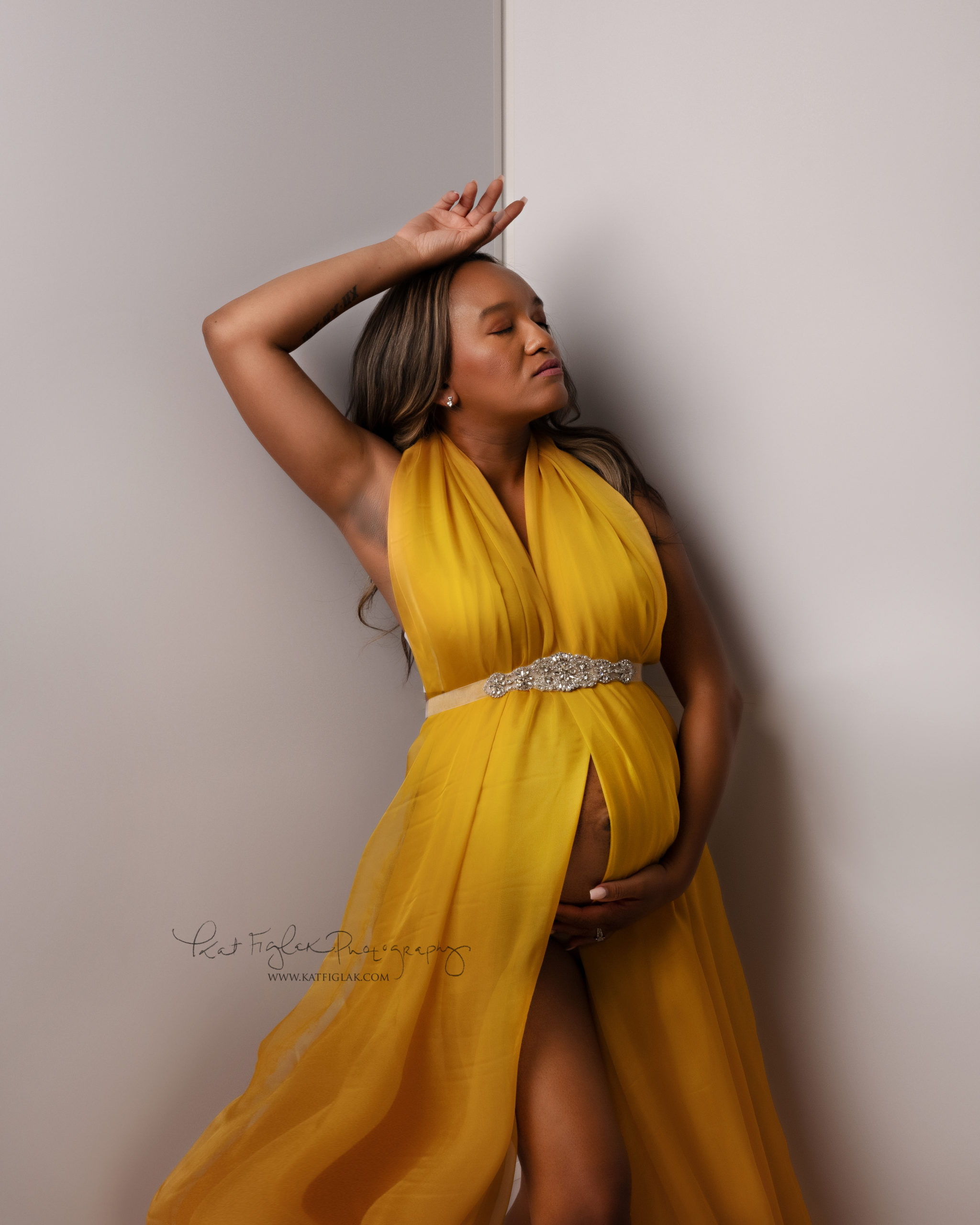 mom wearing a yellow maternity gown with beaded sash
