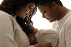 Mother and father with their foreheads together looking down at their newborn baby boy