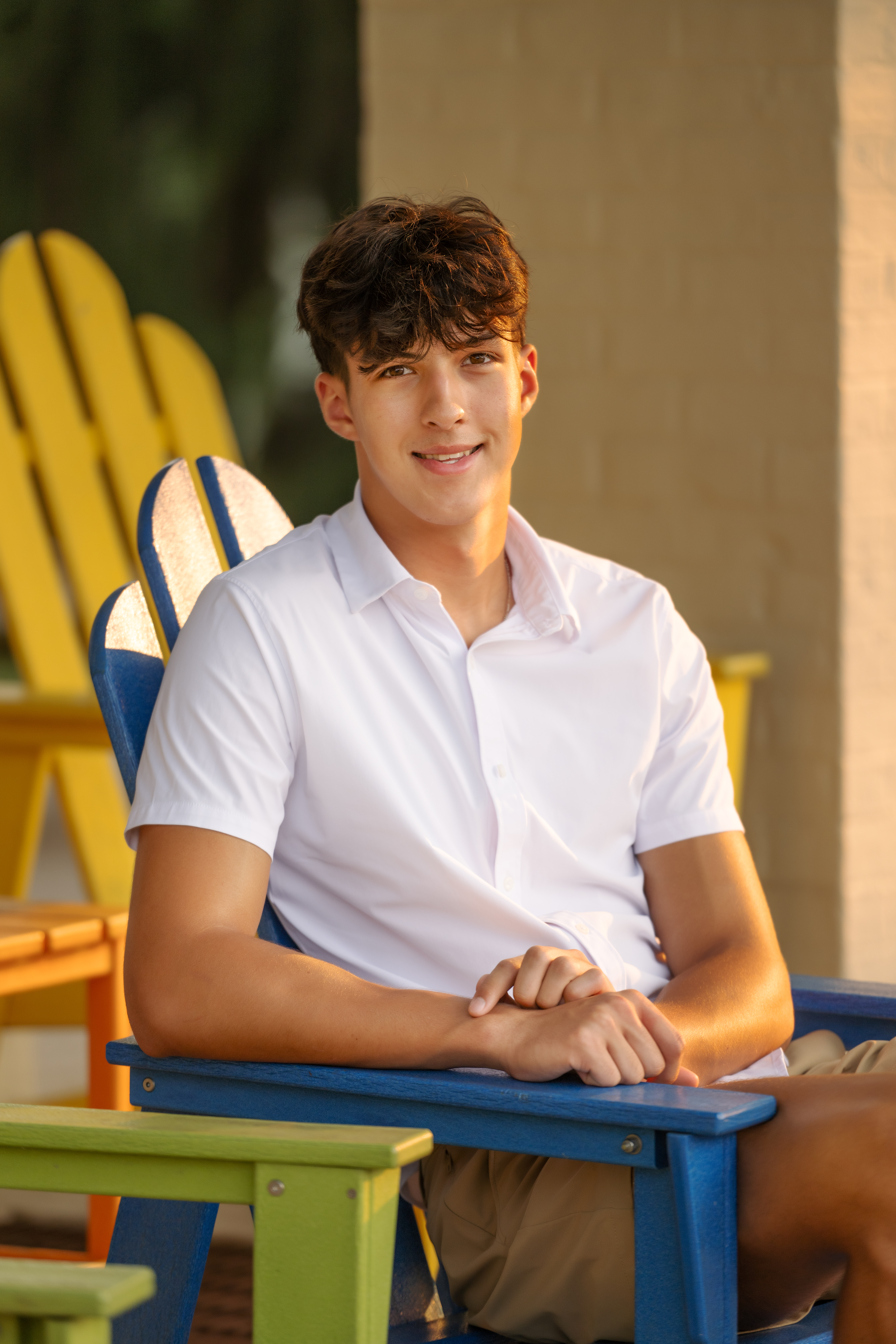 Flint Powers Catholic Senior boy wearing a white shirt sitting on a blue chair