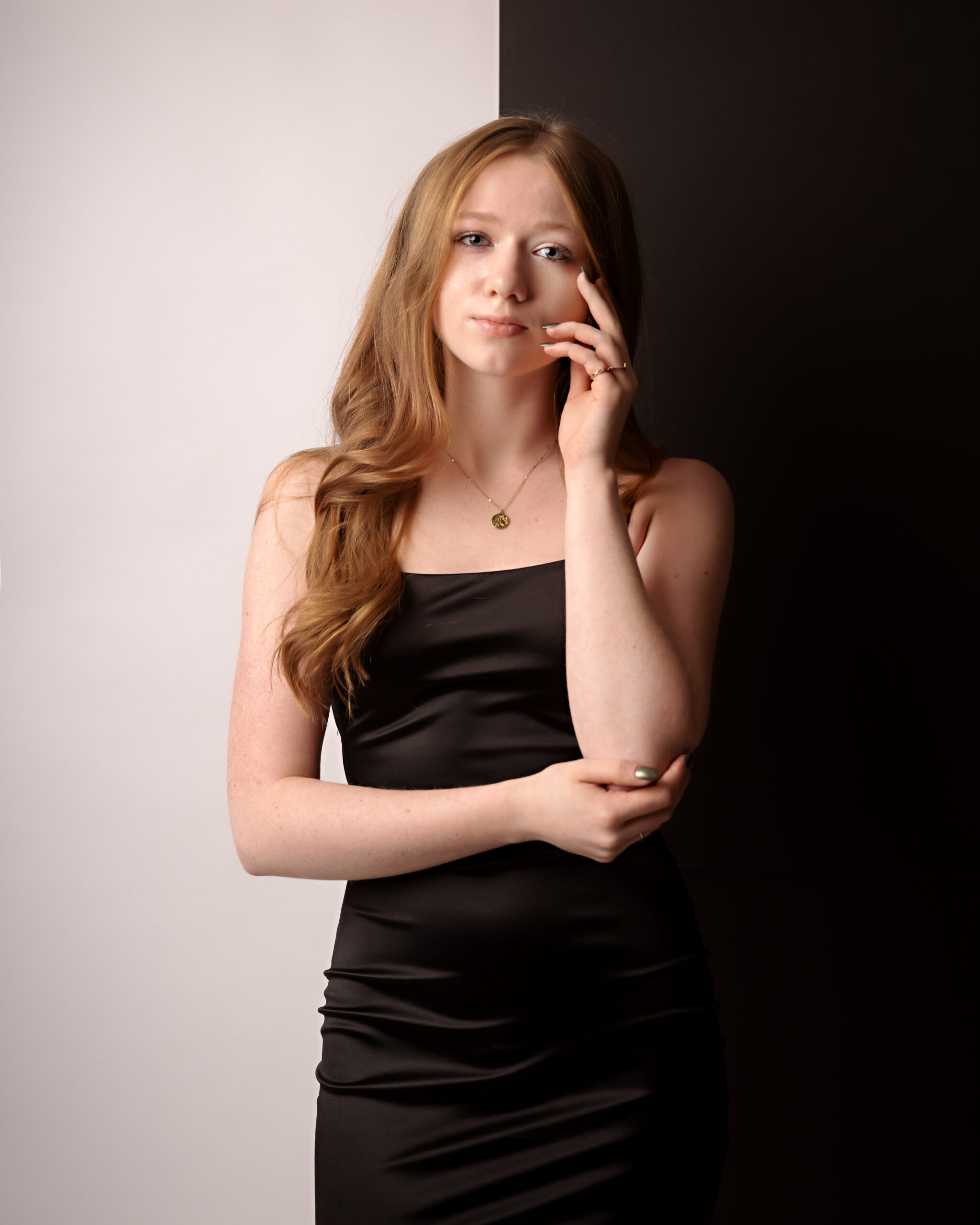 Lake Orion, high school, senior girl with strawberry blonde hair, wearing a black dress standing in front of a split black and white studio backdrop